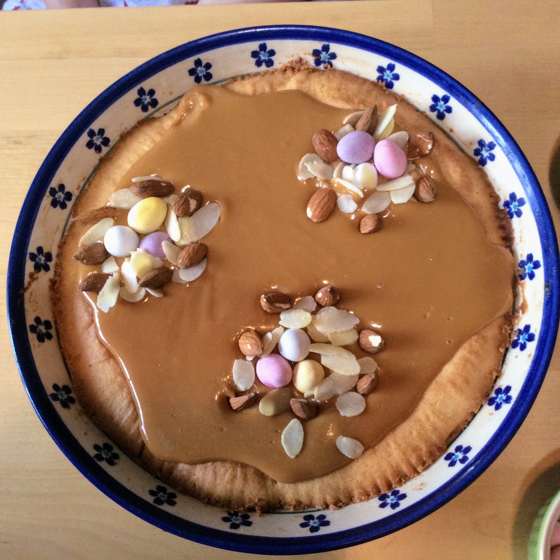 Round Polish Mazurek Easter cake decorated with caramel, almonds, chocolate eggs.
