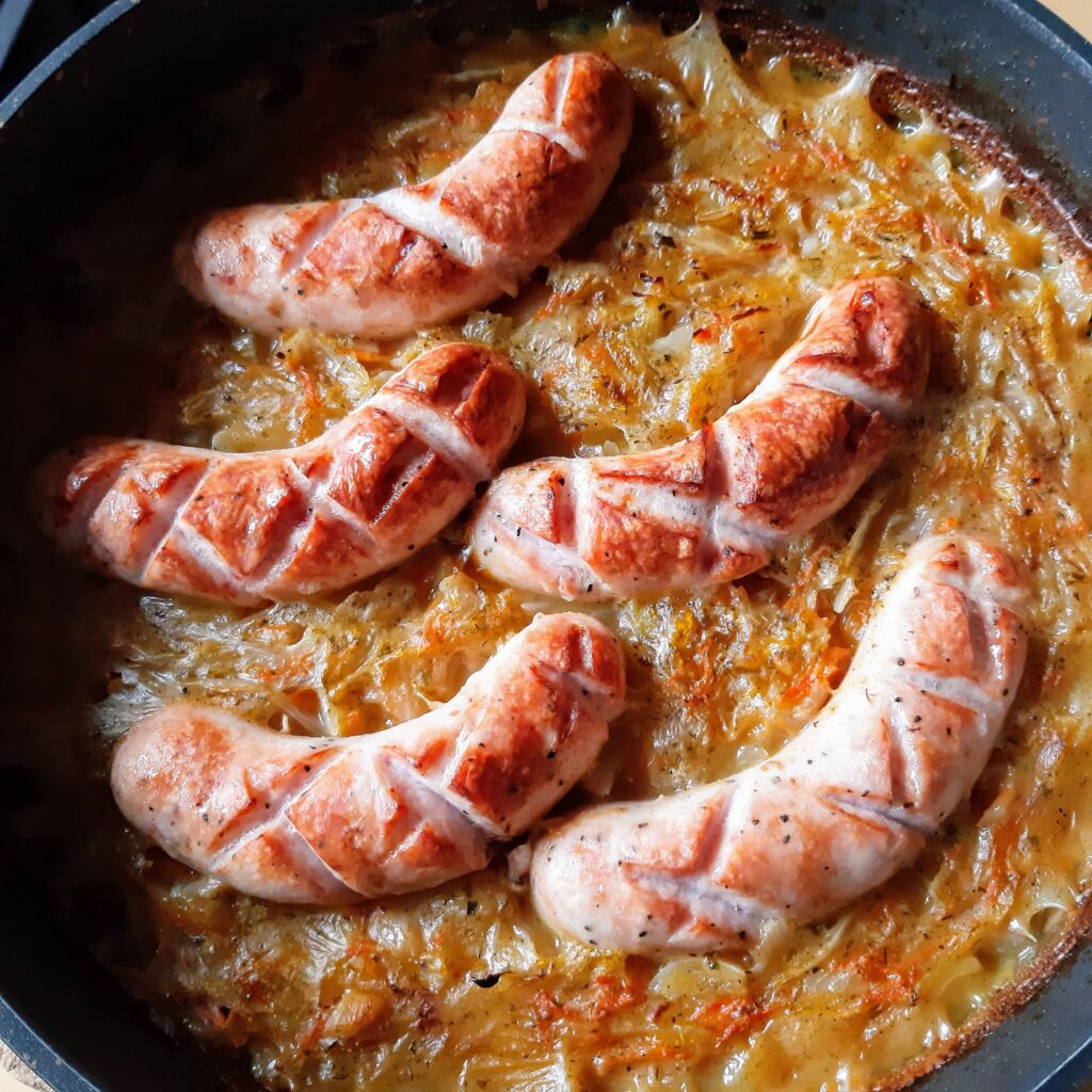 A black pot of cabbage and Polish white sausage, browned and straight out of the oven.
